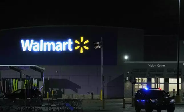 Law enforcement officers are seen stationed outside a Walmart where 11 people were stabbed in a violent attack Saturday, July 26, 2025, in Traverse City, Mich (AP Photo/Ryan Sun)