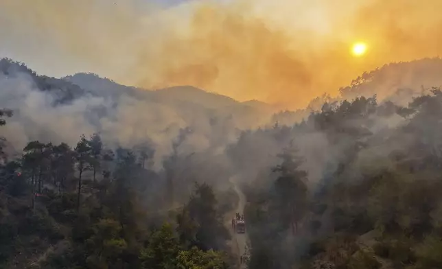 Smoke rises into the sky during a wildfirenear the town of Rabia, Syria, in the Latakia countryside, Sunday, July 6, 2025. (AP Photo/Ghaith Alsayed)