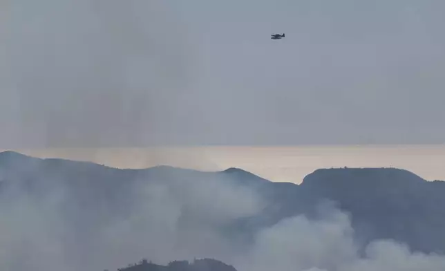 A Turkish firefighting aircraft flies over smoke covered hills as it assists in extinguishing wildfires near the town of Rabia, in Syria's Latakia province, Saturday, July 5, 2025. (AP Photo/Ghaith Alsayed)