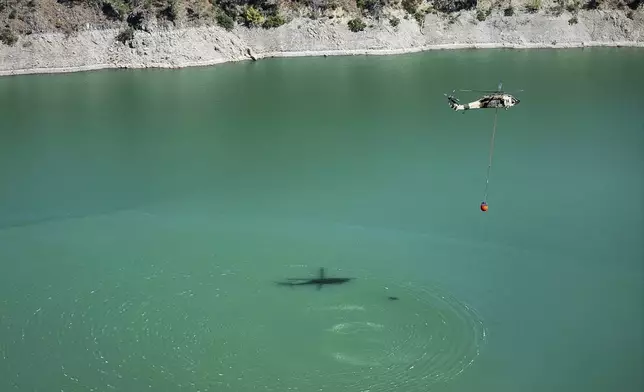 Jordanian Black Hawk helicopters carry out water-filling operations to help extinguish a wildfire near the town of Rabia, in Syria's Latakia countryside, Sunday, July 6, 2025. (AP Photo/Ghaith Alsayed)