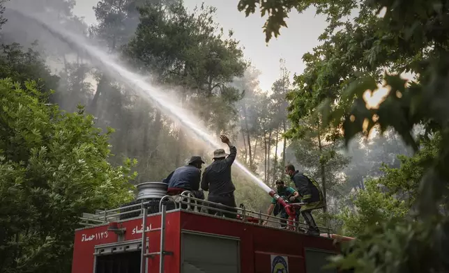 An emergency responder with the Syrian Civil Defense, known as the White Helmets, works to extinguish a wildfire near the town of Rabia, in Syria's Latakia countryside, Sunday, July 6, 2025. (AP Photo/Ghaith Alsayed)