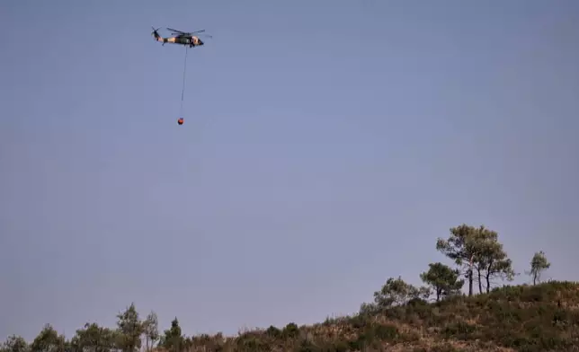 Jordanian Black Hawk helicopters carry out water-filling operations to help extinguish a wildfire near the town of Rabia, in Syria's Latakia countryside, Sunday, July 6, 2025. (AP Photo/Ghaith Alsayed)