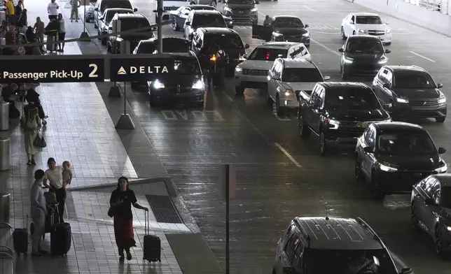 Travelers arrive and depart a terminal at Detroit Metropolitan Airport in Romulus, Mich., Thursday, July 3, 2025. (AP Photo/Paul Sancya)