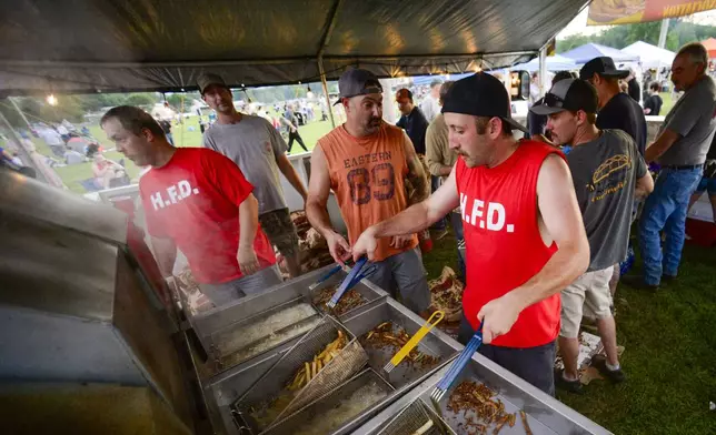 Members of the Hinsdale, N.H., Fire Department make fresh fries during the annual fireworks show on Thursday, July 3, 2025. (Kristopher Radder/The Brattleboro Reformer via AP)