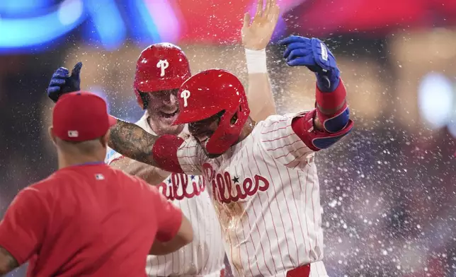 Philadelphia Phillies' Edmundo Sosa, right, celebrates with teammates after the Phillies won a baseball game against the Boston Red Sox on catcher's interference with the bases loaded in the 10th inning Monday, July 21, 2025, in Philadelphia. (AP Photo/Matt Slocum)