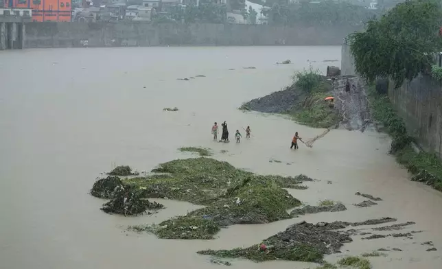 A man throws a fishing net along a swollen river following tropical storm Wipha fueled monsoon rains in Marikina, Philippines on Tuesday, July 22, 2025. (AP Photo/Aaron Favila)