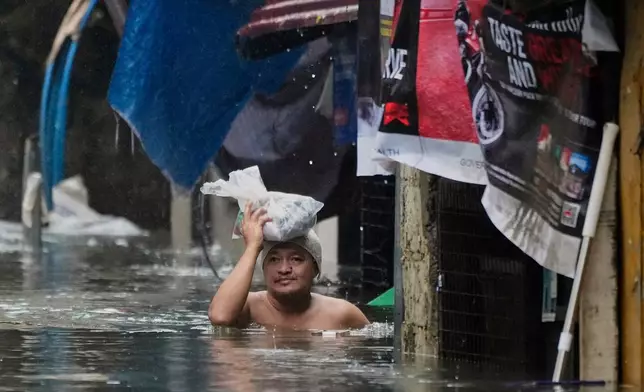A man wades along chest-deep flood waters following tropical storm Wipha fueled monsoon rains in Quezon city, Philippines on Tuesday, July 22, 2025. (AP Photo/Aaron Favila)