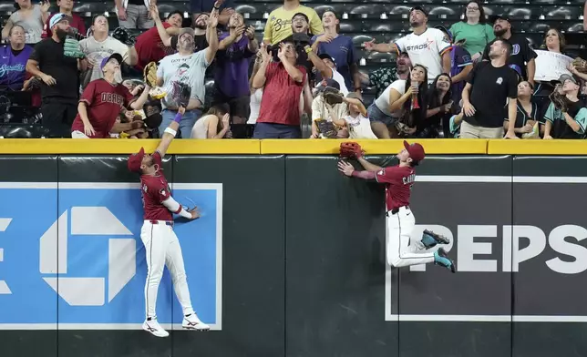 Arizona Diamondbacks left fielder Lourdes Gurriel Jr., left, and Diamondbacks center fielder Corbin Carroll leap in vain for a three-run home run hit by Houston Astros' Brice Matthews during the second inning of a baseball game Monday, July 21, 2025, in Phoenix. (AP Photo/Ross D. Franklin)