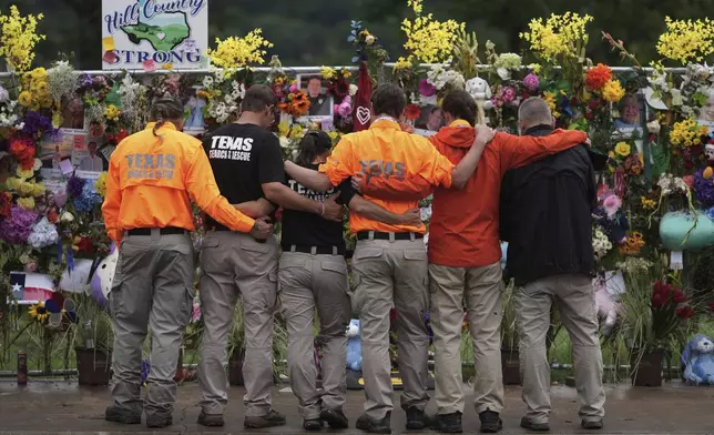 Members of a search and rescue team embrace as they visit a memorial wall for flood victims, Sunday, July 13, 2025, in Kerrville, Texas. (AP Photo/Eric Gay)