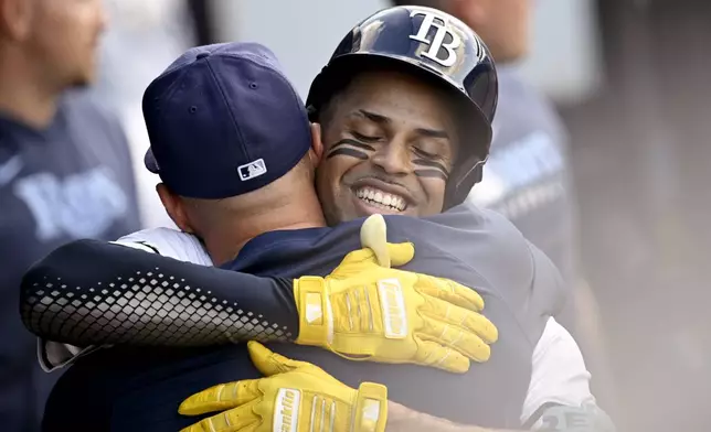 Tampa Bay Rays' Christopher Morel, right, celebrates in the dugout after his solo home run during the second inning of a baseball game against the Athletics Tuesday, July 1, 2025, in Tampa, Fla. (AP Photo/Jason Behnken)