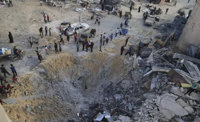 Palestinians inspect the site struck by an Israeli bombardment in Muwasi, Khan Younis, Gaza Strip, Monday, July 28, 2025. (AP Photo/Mariam Dagga)