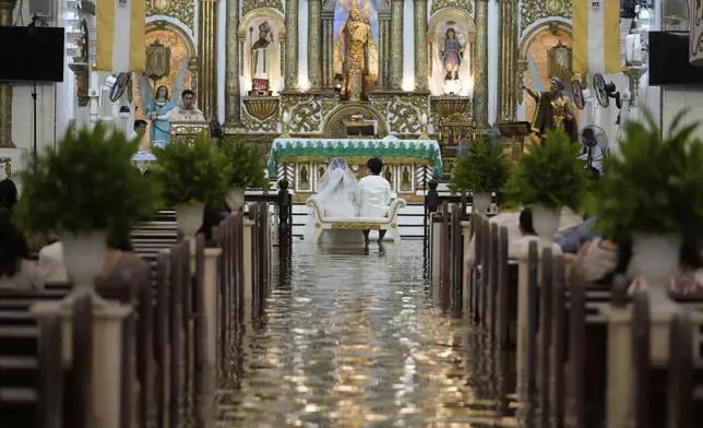 Jade Rick Verdillo right, and Jamaica sit for their wedding ceremony at the flooded Barasoain church in Malolos, Bulacan province, Philippines on Tuesday, July 22, 2025. (AP Photo/Aaron Favila)