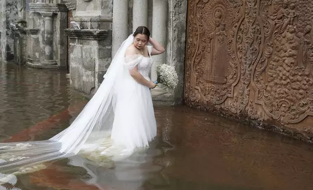 Bride Jamaica Agular prepares to enter the flooded Barasoain church for her wedding in Malolos, Bulacan province, Philippines on Tuesday, July 22, 2025. (AP Photo/Aaron Favila)