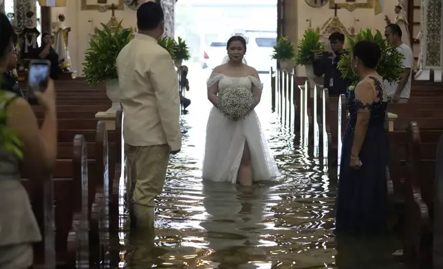 Bride Jamaica Agular walks down the aisle during her wedding at the flooded Barasoain church in Malolos, Bulacan province, Philippines on Tuesday, July 22, 2025. (AP Photo/Aaron Favila)