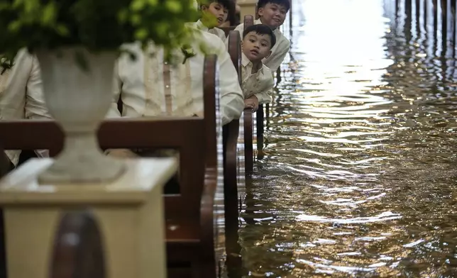 Guests attend a wedding at the flooded Barasoain church in Malolos, Bulacan province, Philippines on Tuesday, July 22, 2025. (AP Photo/Aaron Favila)