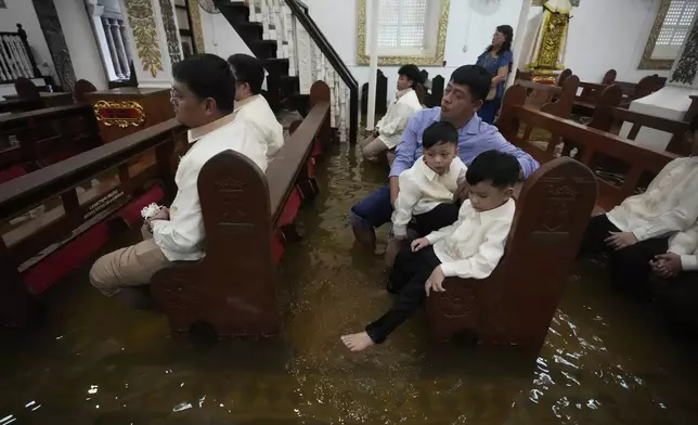 Guests attend a wedding at the flooded Barasoain church in Malolos, Bulacan province, Philippines on Tuesday, July 22, 2025. (AP Photo/Aaron Favila)