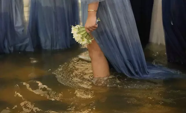 A wedding guest holds a flower during a wedding at the flooded Barasoain church in Malolos, Bulacan province, Philippines on Tuesday, July 22, 2025. (AP Photo/Aaron Favila)