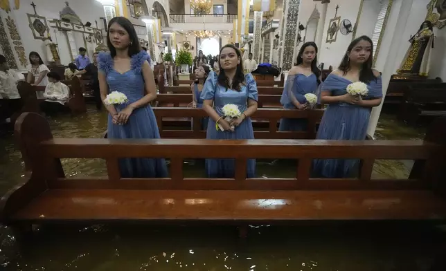 Bridemaids attend a wedding ceremony at the flooded Barasoain church in Malolos, Bulacan province, Philippines on Tuesday, July 22, 2025. (AP Photo/Aaron Favila)