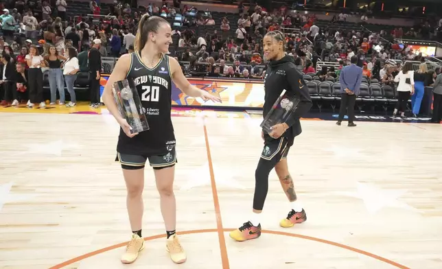 New York Liberty's Sabrina Ionescu, left, holds the 3-point contest trophy while New York Liberty's Natasha Cloud holds the skills challenge trophy during the WNBA All-Star basketball weekend, Friday, July 18, 2025, in Indianapolis. (AP Photo/Michael Conroy)