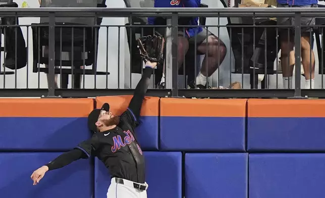 New York Mets' Brandon Nimmo leaps for a ball hit by Cincinnati Reds' Matt McLain for a two-run home run during the fifth inning of a baseball game Friday, July 18, 2025, in New York. (AP Photo/Frank Franklin II)