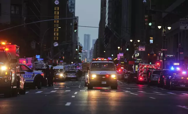 Emergency response vehicles crowd 52nd Street outside a Manhattan office building where two people were shot, including a New York police officer, Monday, July 28, 2025, in New York. (AP Photo/Angelina Katsanis)