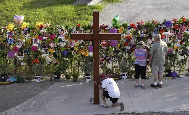 Dan Beazley, of Mich., prays with a large cross at a memorial for flood victims on Thursday, July 10, 2025, in Kerrville, Texas. (AP Photo/Ashley Landis)