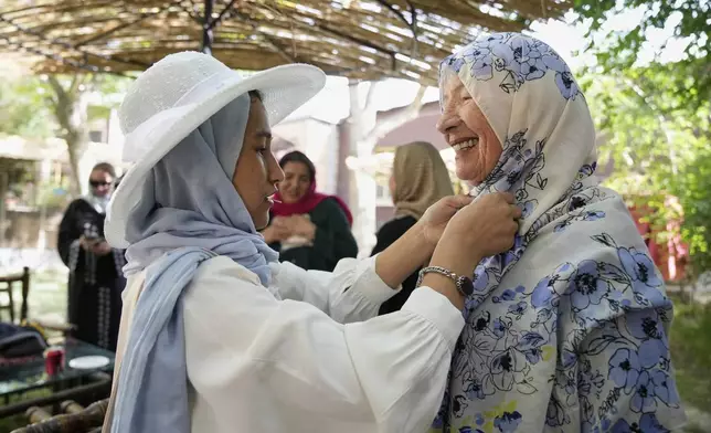 Maryam, a young Afghan on her first day of training to become a tour guide, helps 82-year-old Australian tourist Suzanne Sandral adjust her hijab in Kabul, Afghanistan, Wednesday, May 28, 2025. (AP Photo/Ebrahim Noroozi)