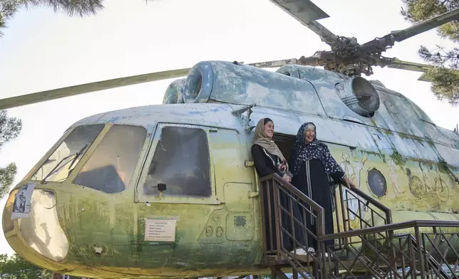 Afghan tour guide Somaya Moniry, 24, left, and 82-year-old Australian tourist Suzanne Sandral pose for a photo next to a military helicopter during a visit to the War Museum in Kabul, Afghanistan, Wednesday, May 28, 2025. (AP Photo/Ebrahim Noroozi)