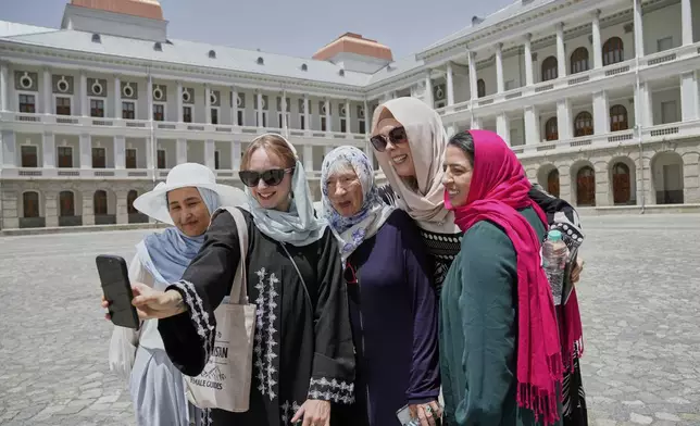 Zoe Stephens, 31, from Britain, takes a selfie with other foreign, female tourists and Maryam, a local trainee tour guide, at left, at Darul Aman Palace in Kabul, Afghanistan, Wednesday, May 28, 2025. (AP Photo/Ebrahim Noroozi)