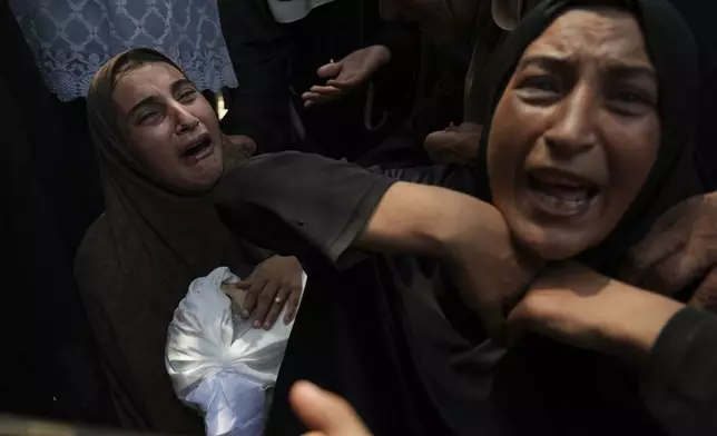 Maysara Adwan, left, mourns as she holds the body of her 11-year-old son, Qais, who was killed in an Israeli airstrike on a school in Gaza that has been used as a shelter, during his burial at Al Shifa Hospital in Gaza City, Friday, July 25, 2025. (AP Photo/Abdel Kareem Hana)