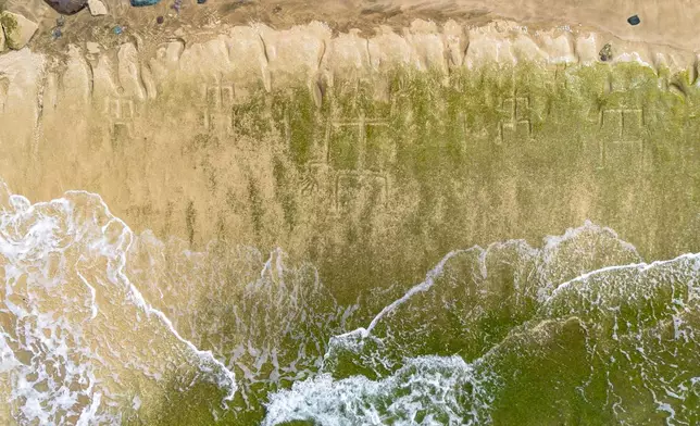 A drone view shows petroglyphs carved into the rock surface at Pokai Bay, July 22, 2025, in Waianae, Hawaii. (AP Photo/Mengshin Lin)