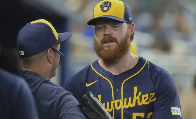 Milwaukee Brewers pitcher Brandon Woodruff (53) talks to a coach at the end of the sixth inning of a baseball game against the Miami Marlins, Sunday, July 6, 2025, in Miami. (AP Photo/Marta Lavandier)