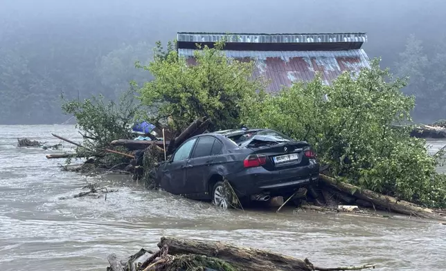 In this image released by the Romanian Emergency Services Suceava (ISU Suceava)a car and house are damaged after a flash flood in the village of Brosteni, northern Romania, Monday, July 28, 2025. (Romanian Emergency Services - ISU Suceava via AP)