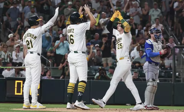 Athletics' Brent Rooker, right, celebrates hitting a two-run home run with Nick Kurtz, center, and Tyler Soderstrom, left, at home plate during the fifth inning of a baseball game Saturday, July 12, 2025, in West Sacramento, Calif. (AP Photo/Sara Nevis)