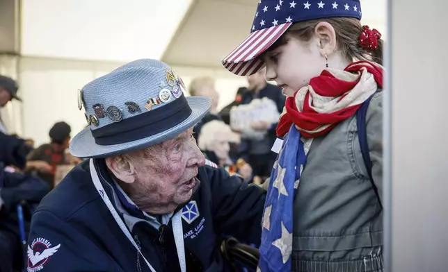 FILE - U.S. veteran SSgt. Jake M. Larson talks to a girl who wears an American flag around her neck during a gathering in preparation of the 79th D-Day anniversary in La Fiere, Normandy, France, June 4, 2023. (AP Photo/Thomas Padilla, file)