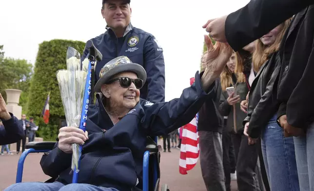 FILE - D-Day veteran Jake Larson, a 102-year-old who is also a star on TikTok, with 1.2 million followers, greets schoolchildren during a visit on June 2, 2025 in Colleville-sur-Mer, to the Normandy American Cemetery that is the final resting place for nearly 9,400 American war dead and which overlooks Omaha beach, one of the D-D-day invasion zones on June 6, 1944. (AP Photo/John Leicester, File)