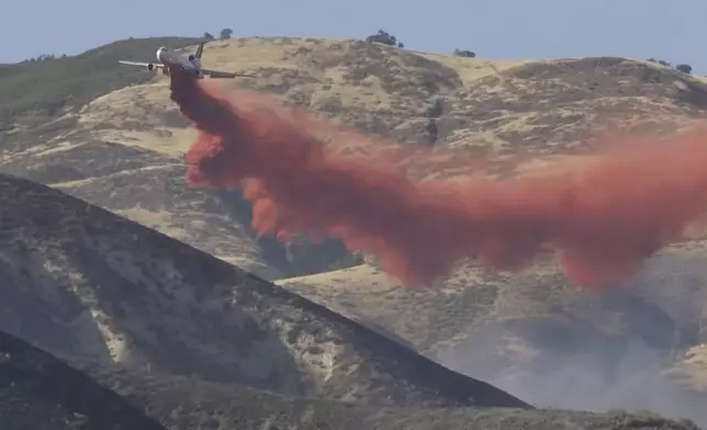 In this image taken from video shows a plane dropping fire retardant the Madre Fire in southeastern San Luis Obispo County, central Calif., July 2, 2025. (KEYT via AP)