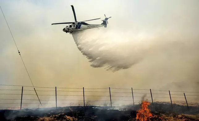A helicopter drops water on the Madre Fire as it burns along Highway 166 on Thursday, July 3, 2025, in San Luis Obispo County, Calif. (AP Photo/Noah Berger)