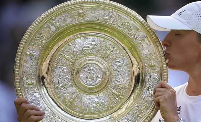 Poland's Iga Swiatek kisses the trophy after beating Amanda Anisimova of the U.S. to win the women's singles final at the Wimbledon Tennis Championships in London, Saturday, July 12, 2025. (AP Photo/Kin Cheung)