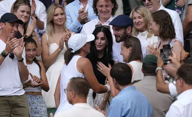 Courteney Cox, center, and Johnny McDaid celebrate with Poland’s Iga Swiatek as she greets her coaches, friends and family after beating Amanda Anisimova of the U.S. to win the women’s singles final at the Wimbledon Tennis Championships in London, Saturday, July 12, 2025.(Andrew Matthews, PA via AP)