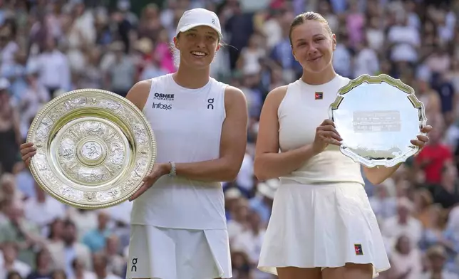 Poland's Iga Swiatek, left, celebrates with the trophy after beating Amanda Anisimova of the U.S., right, to win the women's singles final at the Wimbledon Tennis Championships in London, Saturday, July 12, 2025. (AP Photo/Kin Cheung)