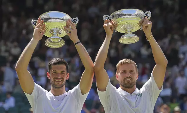 Julian Cash of Britain, left, and Lloyd Glasspool of Britain celebrate with the trophy after winning the men's doubles final match against Rinky Hijikata of Australia and David Pel of the Netherlands at the Wimbledon Tennis Championships in London, Saturday, July 12, 2025. (AP Photo/Kin Cheung)