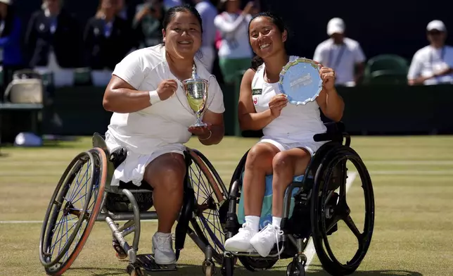 Wang Ziying of China celebrates, left, with the trophy after beating Yui Kamiji of Japan, right, to win the final women's wheelchair singles match at the Wimbledon Tennis Championships in London, Saturday, July 12, 2025. (John Walton/PA via AP)