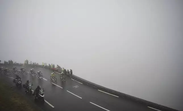 Slovenia's Tadej Pogacar, wearing the overall leader's yellow jersey, in second position, speeds downhill during the fourteenth stage of the Tour de France cycling race over 182.6 kilometers (113.5 miles) with start in Pau and finish in Luchon Superbagneres, France, Saturday, July 19, 2025. (AP Photo/Thibault Camus)