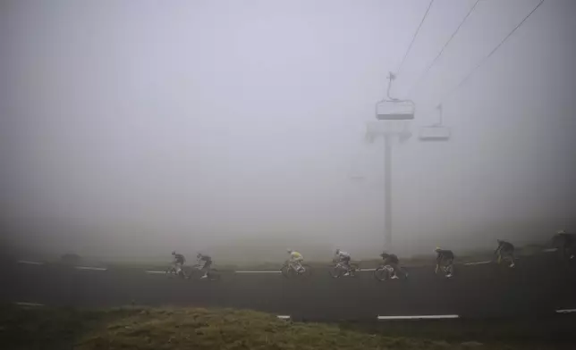 Slovenia's Tadej Pogacar, wearing the overall leader's yellow jersey, center, speeds down Tourmalet pass during the fourteenth stage of the Tour de France cycling race over 182.6 kilometers (113.5 miles) with start in Pau and finish in Luchon Superbagneres, France, Saturday, July 19, 2025. (AP Photo/Thibault Camus)