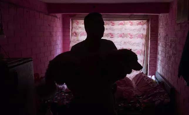 Babu Tamang carries his dog Shayam while playing in their small rented house in Kathmandu, Nepal, Thursday, July 24, 2025. (AP Photo/Niranjan Shrestha)