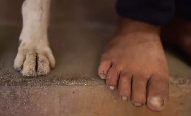 The feet of Babu Tamang and his dog Shyam are seen as they both take a nap before heading out to work in their small rented house in Kathmandu, Nepal, Thursday, July 24, 2025. (AP Photo/Niranjan Shrestha)