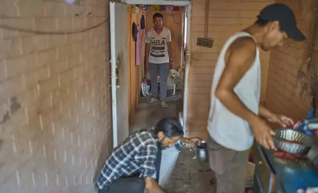 Babu Tamang arrives with his canine Shayam as his apartment mates prepare lunch in their small rented house in Kathmandu, Nepal, Thursday, July 3, 2025. (AP Photo/Niranjan Shrestha)
