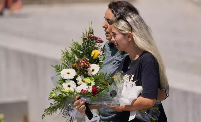 Family and friends of Liverpool forward Diogo Jota and his brother, hold flowers as they arrive at a church where their bodies have been brought for a wake and funeral, in Gondomar, near Porto, Portugal, on Friday, July 4, 2025. (AP Photo/Manu Fernandez)