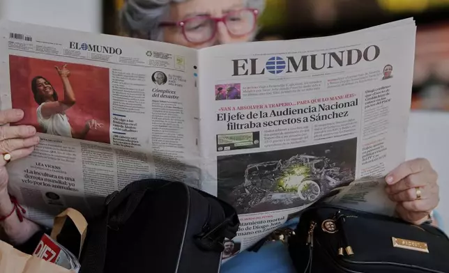 A woman at Adolfo Suarez Madrid-Barajas Airport in Madrid, reads a newspaper showing on its front page the car involved in the crash in which Liverpool player Diogo Jota and his brother died in the north-western city of Zamora, Spain, Friday, July 4, 2025. (AP Photo/Manu Fernandez)